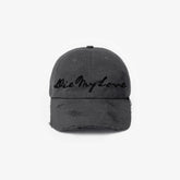 Black distressed baseball cap with 'Die My Love' text on a white background
